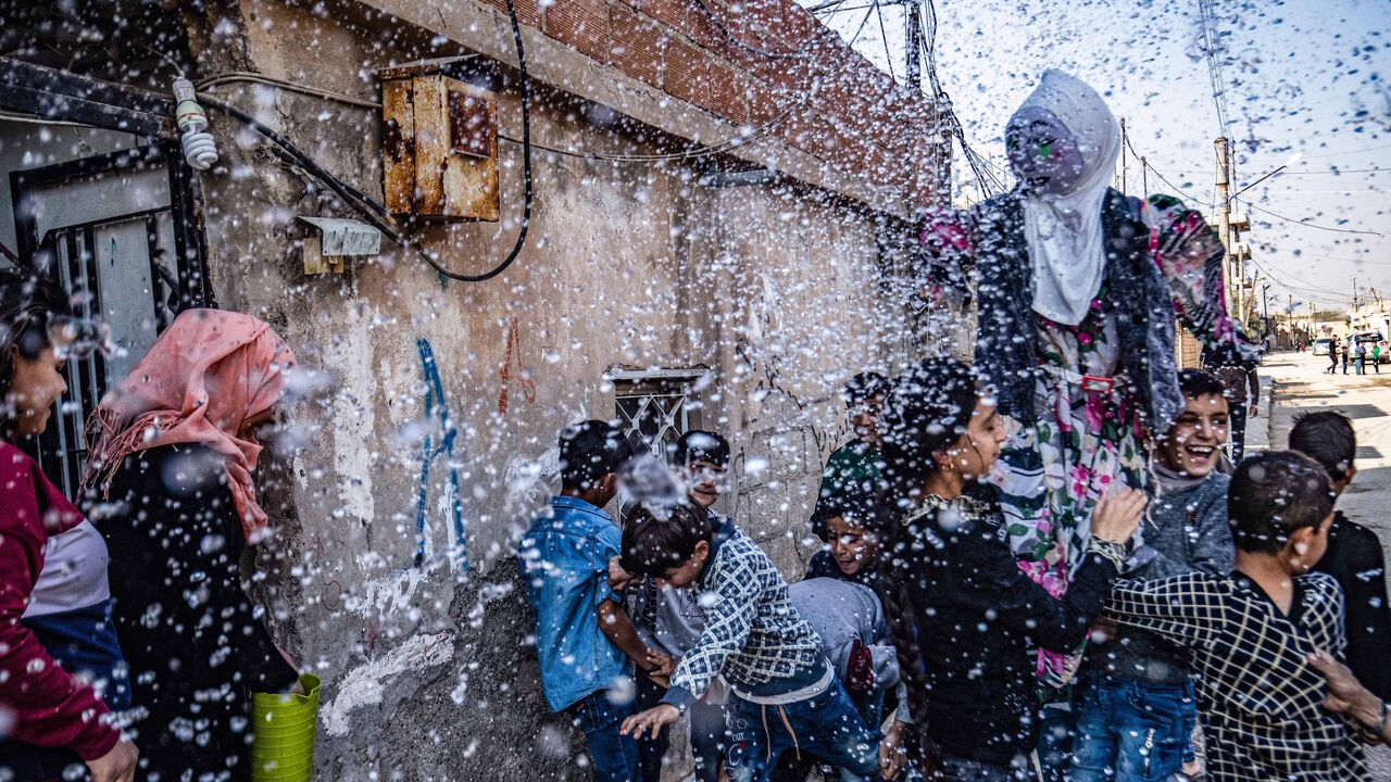 Syrian Kurds parade a doll, made of wood and colorful fabric, as they perform the "Bride of the Rain" ritual in the northeast city of Qamishli on Nov. 19, 2021. 