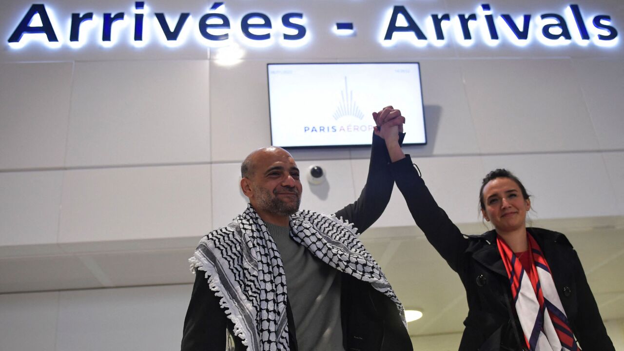 Egyptian-Palestinian political activist Ramy Shaath holds up the arm of his wife, Celine Lebrun-Shaath, as he arrives at Roissy Airport in Roissy, outside Paris, on Jan. 8, 2022.