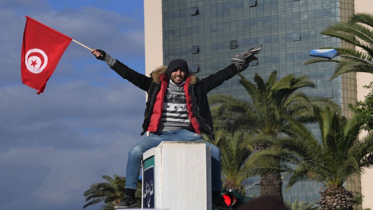 A Tunisian demonstrator waves the national flag at protests against President Kais Saied on the 11th anniversary of the Tunisian revolution in the capital, Tunis, on Jan. 14, 2022.