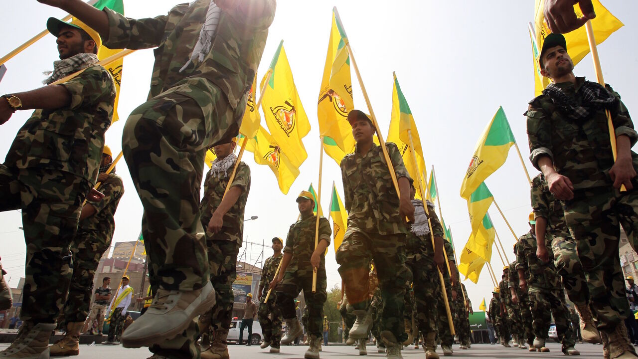 Shiite Muslim men in the military fatigues of Iraq's Kataib Hezbollah wave the party's yellow flags as they march through Baghdad during a parade marking Al-Quds (Jerusalem) International Day on July 25, 2014. 