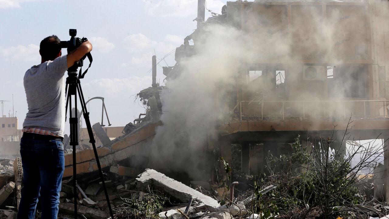 A journalist films the wreckage of a building described as part of the Scientific Studies and Research Centre (SSRC) compound in the Barzeh district, north of Damascus, during a press tour organized by the Syrian information ministry, on April 14, 2018. 