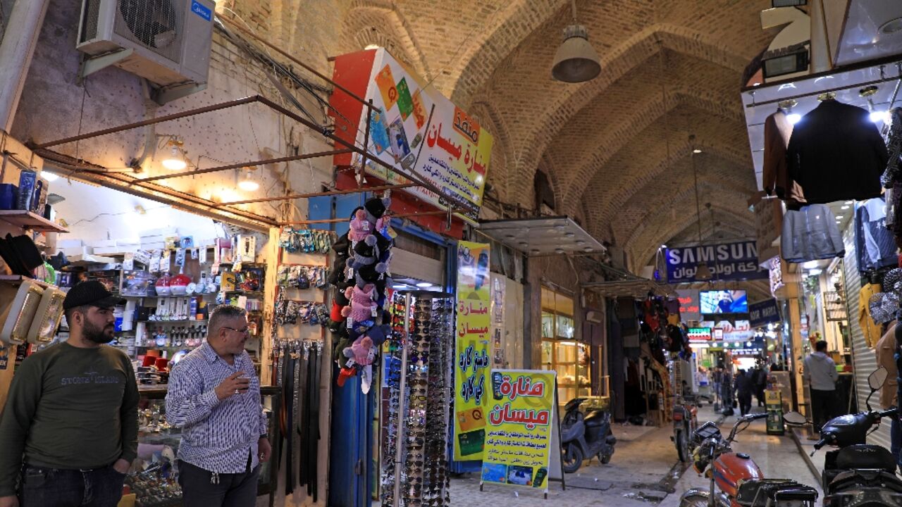 Iraqis walk at a market in the city of Amarah, capital of Iraq's southeastern Maysan province, which is  gripped by a surge in violence