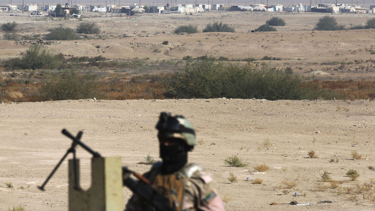 Iraqi soldiers secure buses transporting displaced families from the displaced persons camp in Habbaniyah in Iraq's Anbar province on Nov. 10, 2020.