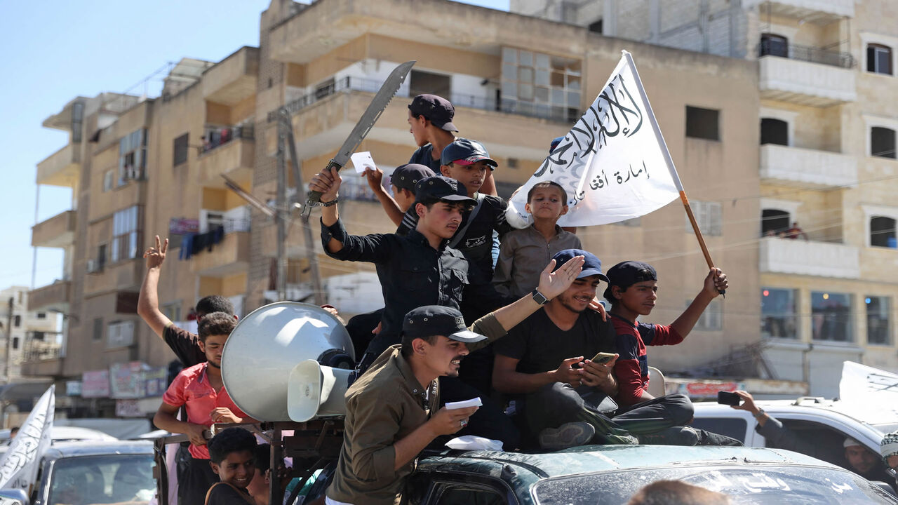 Members of Syria's top jihadist group Hayat Tahrir al-Sham, led by al-Qaeda's former Syria affiliate, parade with their flags and those of the Taliban's declared "Islamic Emirate of Afghanistan" through the rebel-held northwestern city of Idlib, Syria, Aug. 20, 2021.