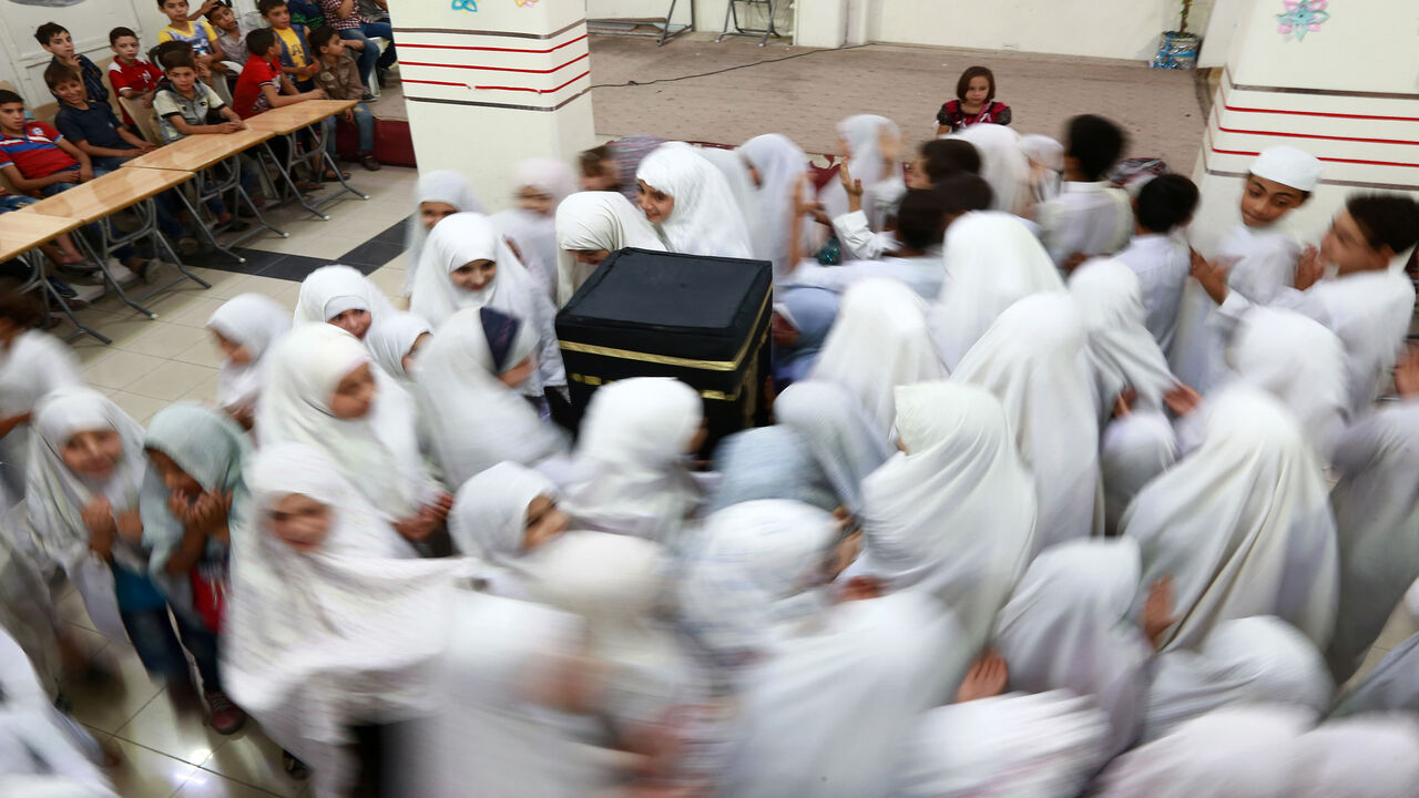 Syrian children circumambulate a model of the Kaaba during an event to teach children the rites of pilgrimage, in the rebel-held town of Douma, eastern outskirts of Damascus, Syria, Aug. 29, 2017.