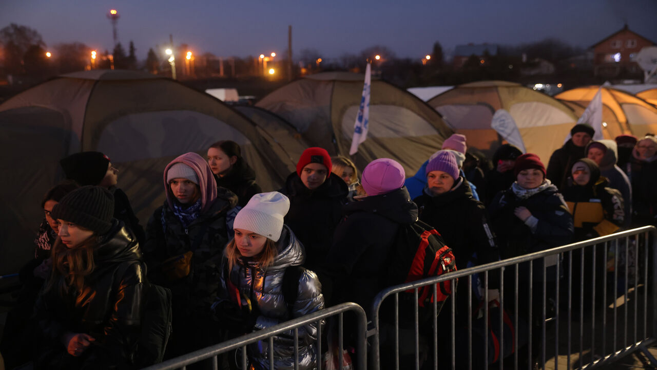 People who have just crossed from war-torn Ukraine into Poland wait to board buses provided by Polish authorities at the Medyka border crossing, Medyka, Poland, March 11, 2022.