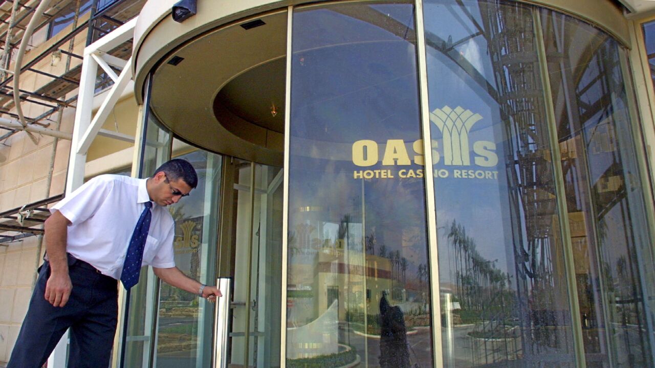 A security guard opens the main entrance to the Oasis Casino on May 3, 2001.