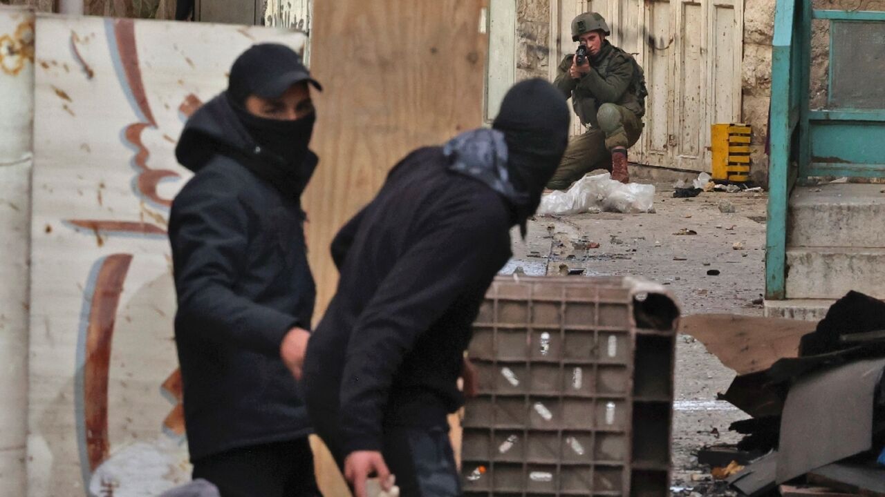 An Israeli soldier takes aim while a Palestinian protester prepares to throw a stone during clashes in Hebron, in the occupied West Bank, on March 4, 2022