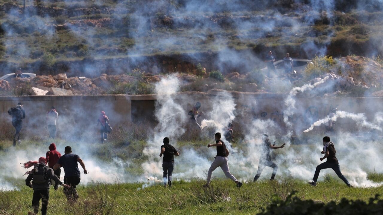 Palestinians run for cover during clashes with Israeli security forces at the northern entrance of Ramallah, near the Israeli settlement of Beit Eil, in the occupied West Bank, on April 11, 2022 Palestinians run for cover during clashes with Israeli security forces at the northern entrance of Ramallah, near the Israeli settlement of Beit Eil, in the occupied West Bank, on April 11, 2022