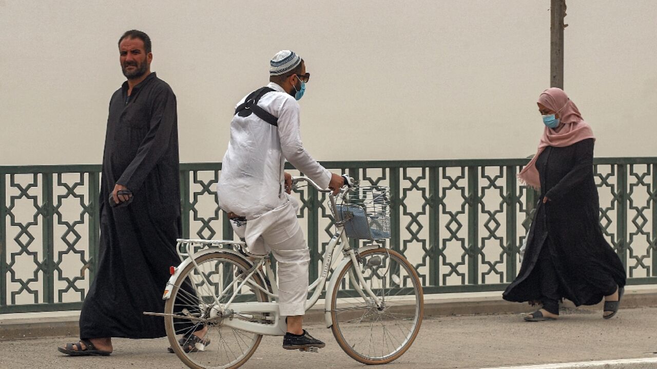 A man rides a bicycle along the Sinek bridge spanning the Tigris river in Iraq's capital Baghdad during a severe dust storm on April 20, 2022 A man rides a bicycle along the Sinek bridge spanning the Tigris river in Iraq's capital Baghdad during a severe dust storm on April 20, 2022