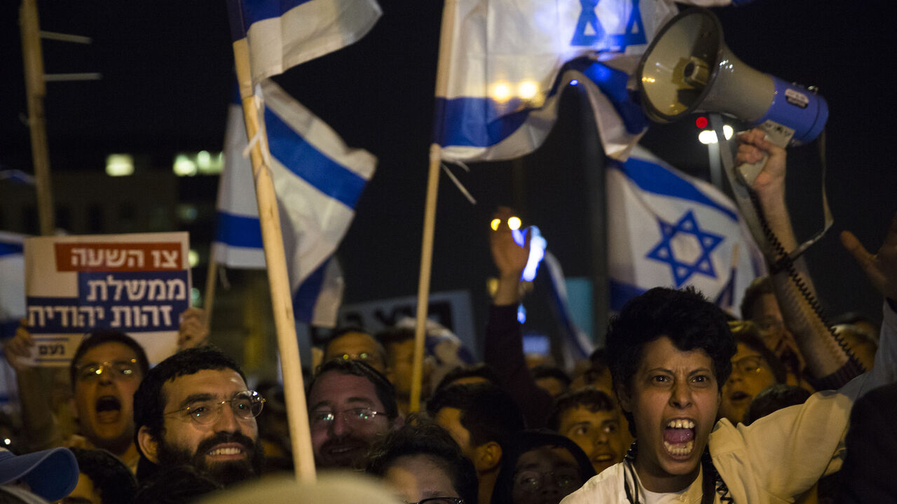 Right-wing Israeli supporters hold signs and flags as they protest against the Israeli government on April 6, 2022, in Jerusalem.