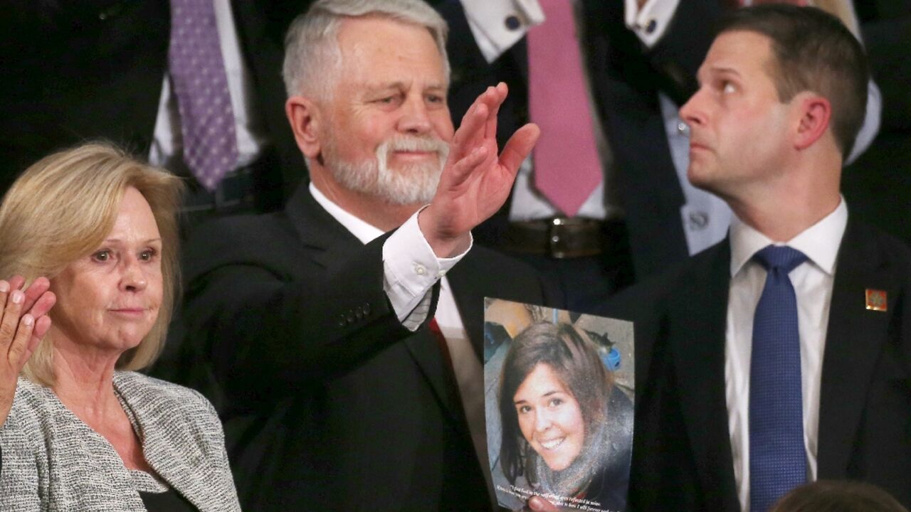 Carl Mueller (C) holds a photo of his daughter, Kayla, as his wife Marsha (L) looks on during the 2020 State of the Union address