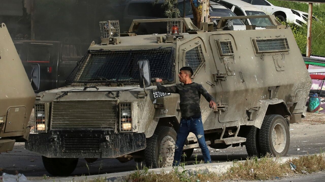 A Palestinian man hurls stones from behind an Israeli security armoured vehicle during a raid to look for wanted Palestinians in Nablus city, in the occupied West Bank A Palestinian man hurls stones from behind an Israeli security armoured vehicle during a raid to look for wanted Palestinians in Nablus city, in the occupied West Bank