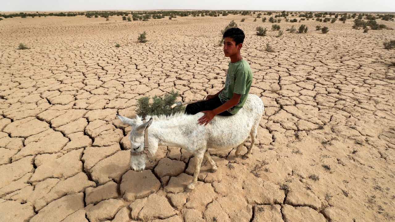 An Iraqi rides a donkey across the dried out lake bed that is all that is left of Lake Hamrin, in normal years a key irrigation reservoir