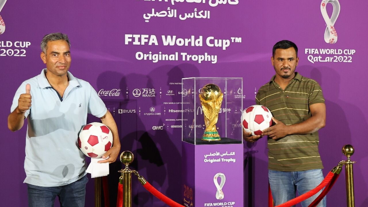 Foreigners pose next to the World Cup trophy in Doha for an event marking 200 days until the 2022 tournament Foreigners pose next to the World Cup trophy in Doha for an event marking 200 days until the 2022 tournament