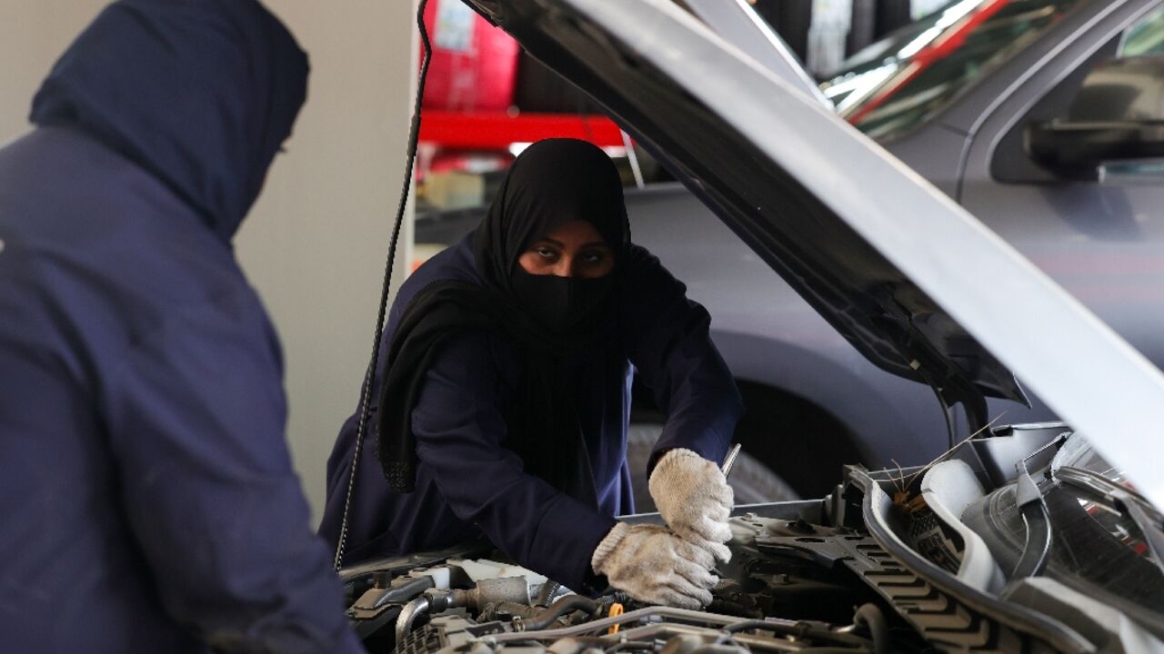 Ghada Ahmed (R) works on a car in Saudi Arabia, where garages are tapping women as a source for mechanics