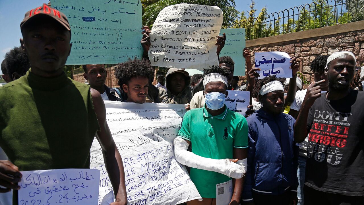 Migrants hold placards during an anti-racism demonstration in the Moroccan capital Rabat on June 28, 2022. 