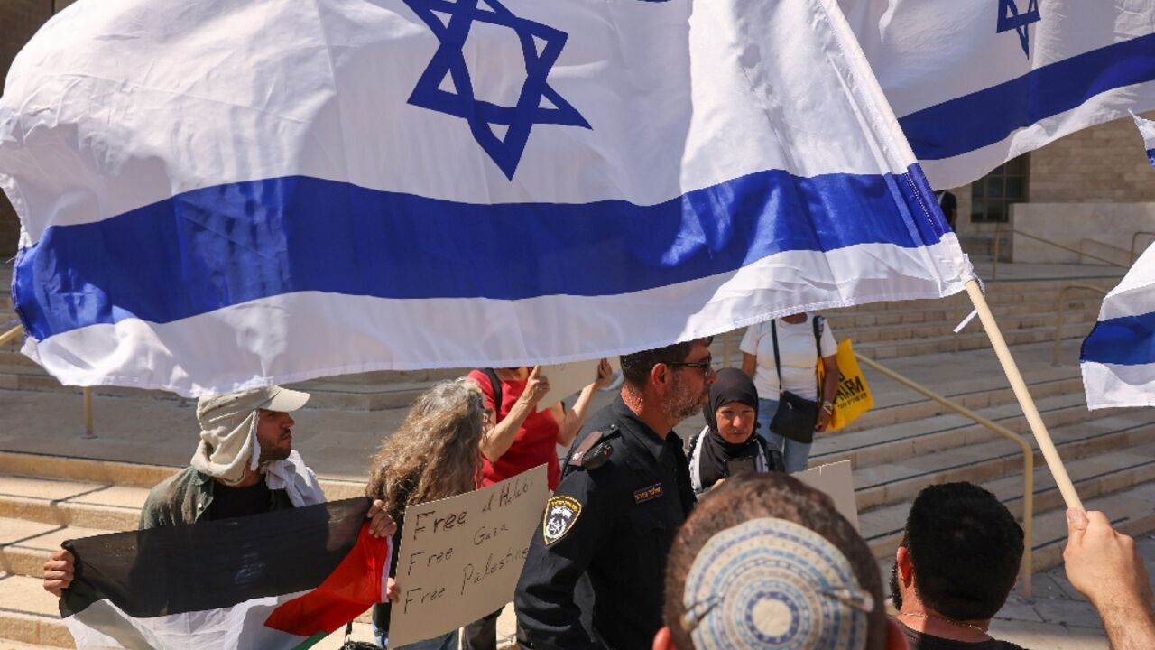 Left-wing activists holding placards and a Palestinian national flag, and right-wing protesters argue outside an Israeli court during the trial of Palestinian Mohammed al-Halabi, the former Gaza director of World Vision, in Beersheba