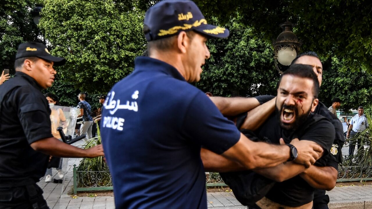 Tunisian policemen arrest a protester during a demonstration during a protest days before  President Kais Saied holds a referendum on a controversial constitution