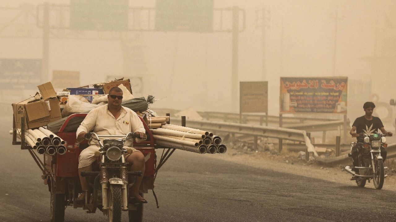 People ride during a sandstorm in the town of Khalis in Iraq's Diyala province on July 3: the country of 41 million, despite the mighty Tigris and Euphrates rivers, also suffers from water shortages and declining rainfall