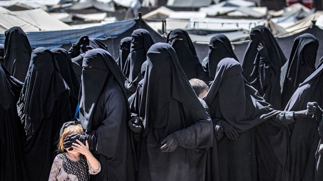 Women and a child queue to receive humanitarian aid packages at the Kurdish-run al-Hol camp.