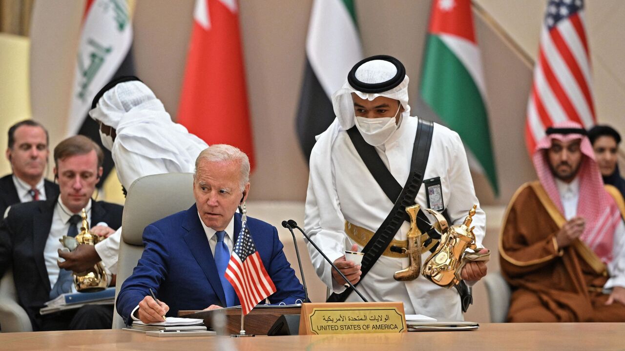 US President Joe Biden takes notes while an usher serves coffee during the Jeddah Security and Development Summit (GCC+3) at a hotel in Saudi Arabia's Red Sea coastal city of Jeddah on July 16, 2022.