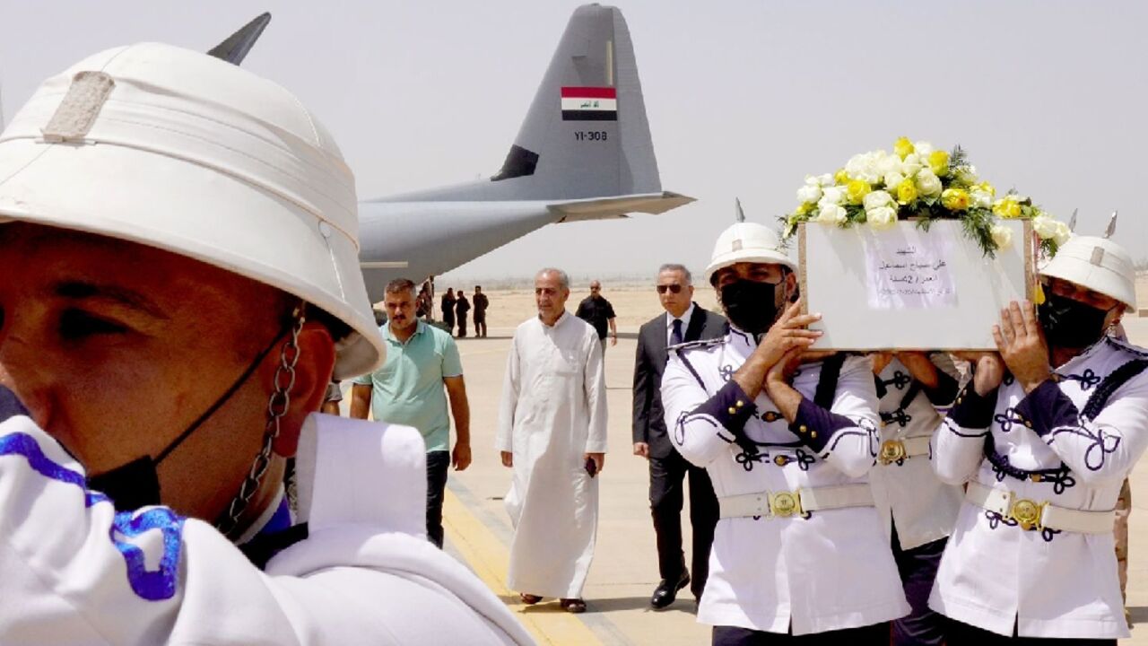 Honour guards at Baghdad airport carry caskets of the victims