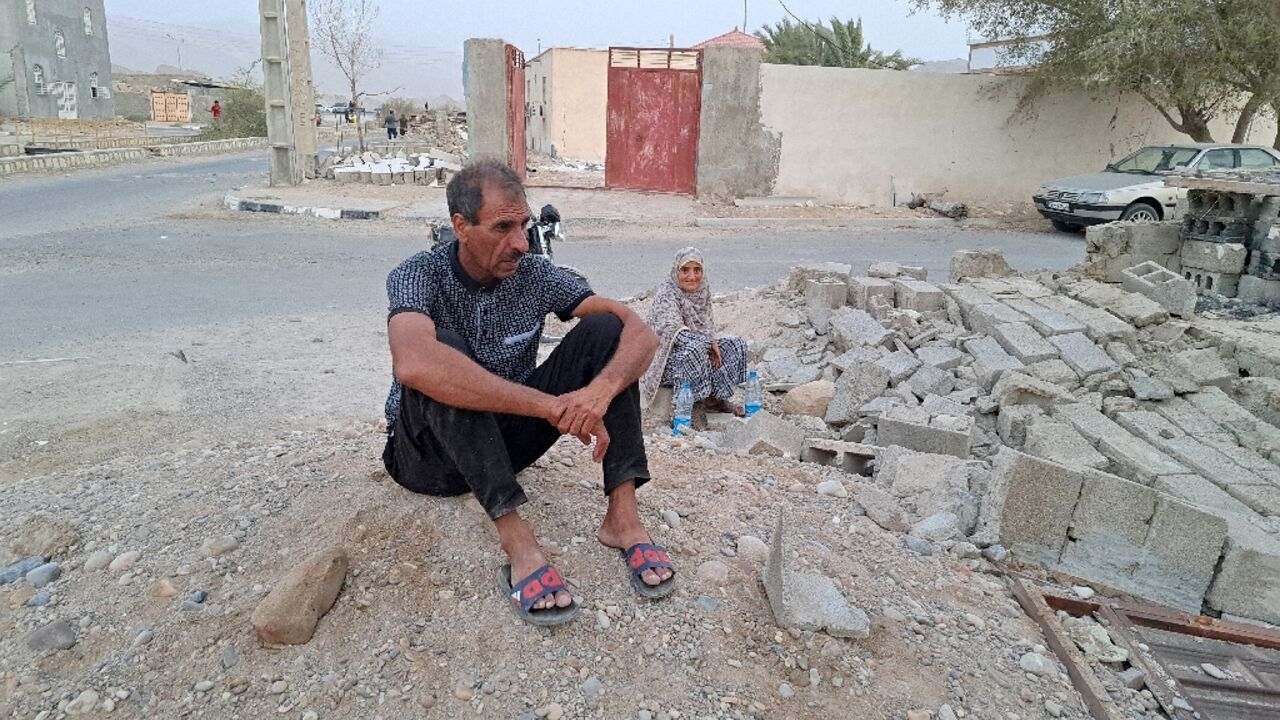 A couple sits in the rubble after earthquakes struck the village of Sayeh Khosh in Iran's southern Hormozgan province A couple sits in the rubble after earthquakes struck the village of Sayeh Khosh in Iran's southern Hormozgan province