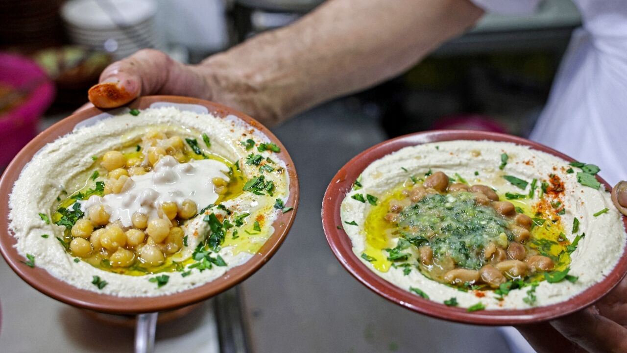 A cook prepares to serve plates of hummus and fava beans at a restaurant in the Old City of Jerusalem