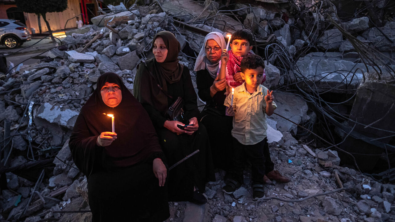 Palestinians hold candles during a rally amid the ruins of houses allegedly destroyed by Israeli airstrikes, Beit Lahia, Gaza City, Gaza Strip, May 25, 2021.