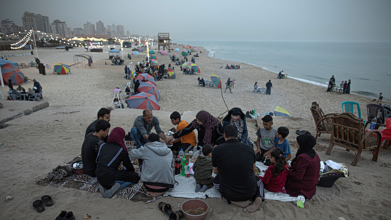 Gazans wait for the sun to set to break their fast on the beach of Gaza City, Gaza Strip, April 29, 2022.