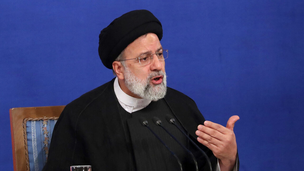 Iranian President Ebrahim Raisi sits near a portrait of Iran's Supreme Leader Ayatollah Ali Khamenei.