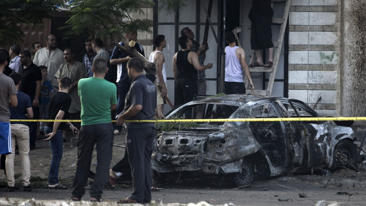 Palestinians gather around a burnt-out car after explosions destroyed five cars belonging to members of Hamas and Islamic Jihad, witnesses and a security source said, Gaza City, Gaza Strip, July 19, 2015.