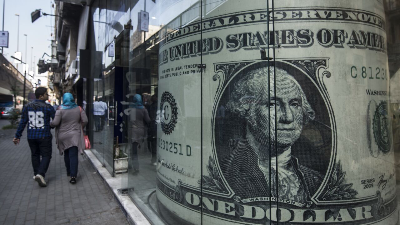 People walk past a currency exchange shop displaying a giant US dollar banknote in downtown Cairo on Nov. 3, 2016.