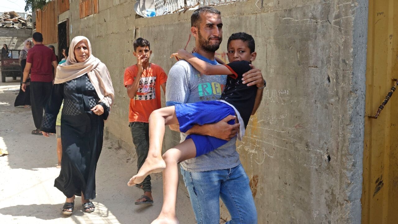 A Palestinian man carries an injured boy following an Israeli air strike, in Khan Yunis in the southern Gaza Strip