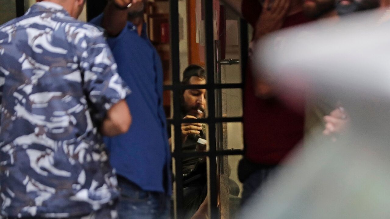 The suspect in a Lebanese bank hostage-taking (C) smokes a cigarette before turning himself in to authorities after the day-long drama over his frozen money