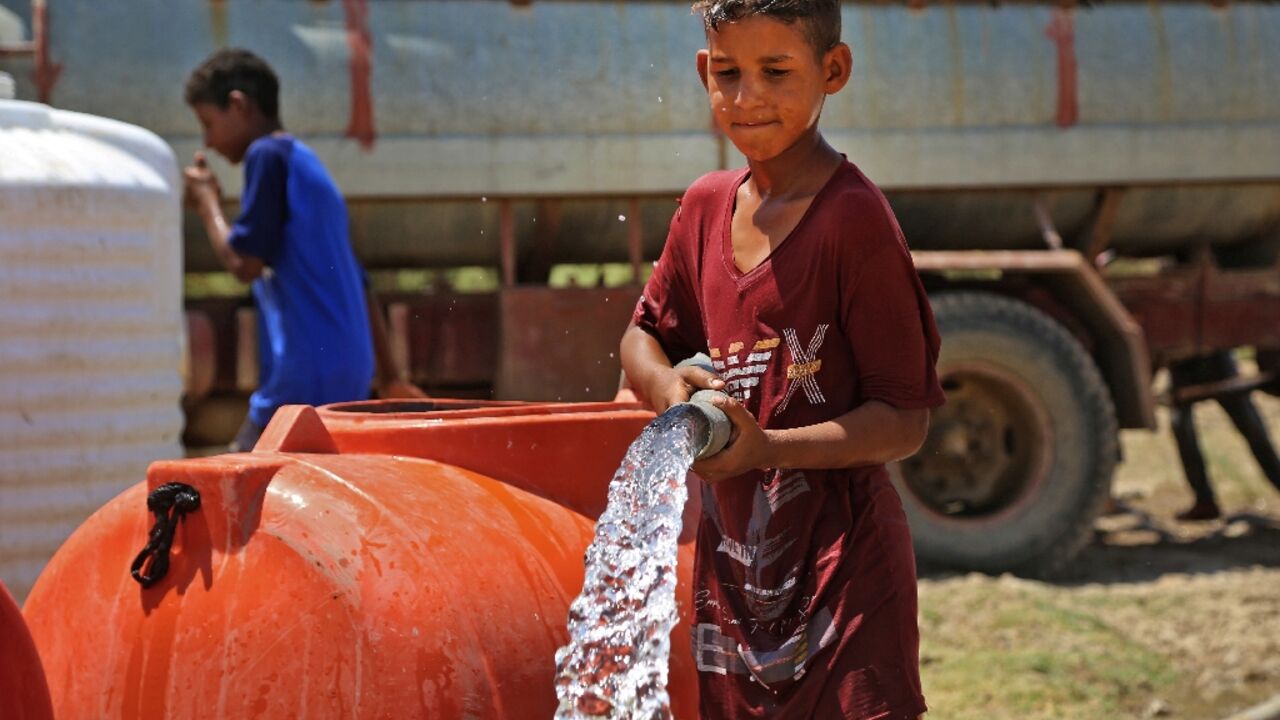 A boy collects water amid shortages and soaring temperature in the Iraqi village of al-Aghawat: dozens of villages depend on sporadic tanker-truck deliveries and salty wells