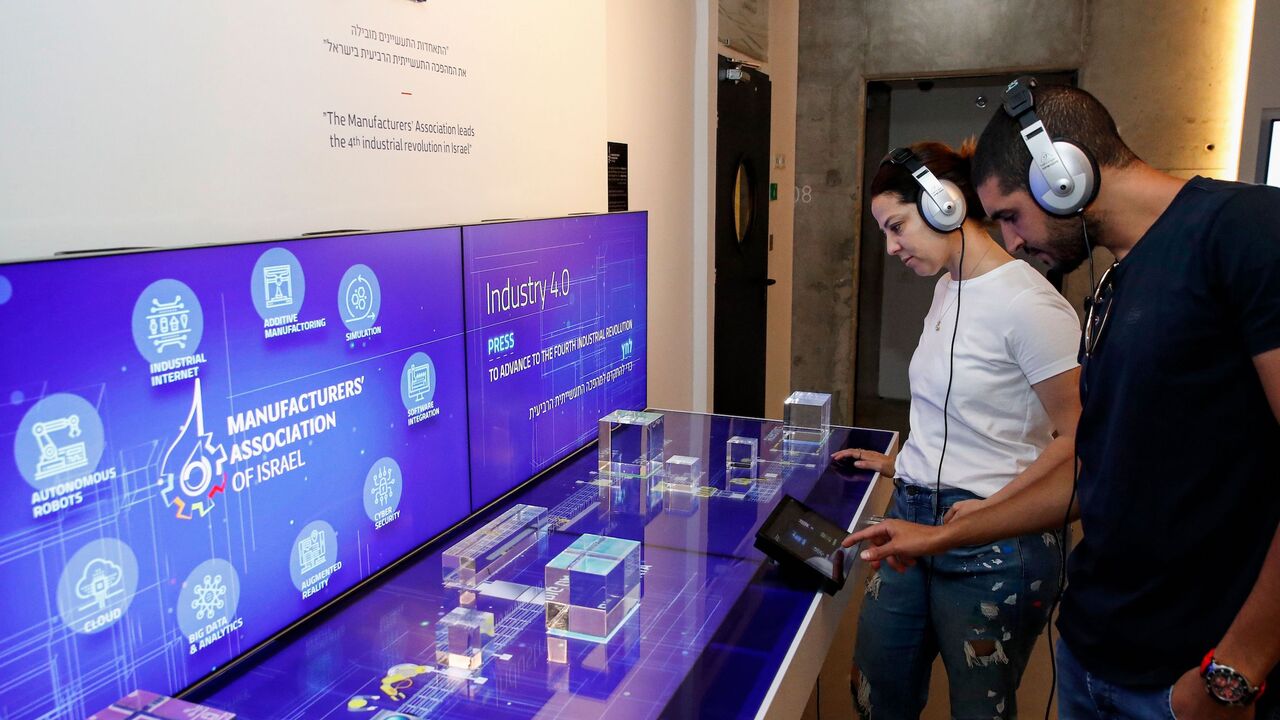 Visitors interact with a display by the Manufacturer's Association of Israel.