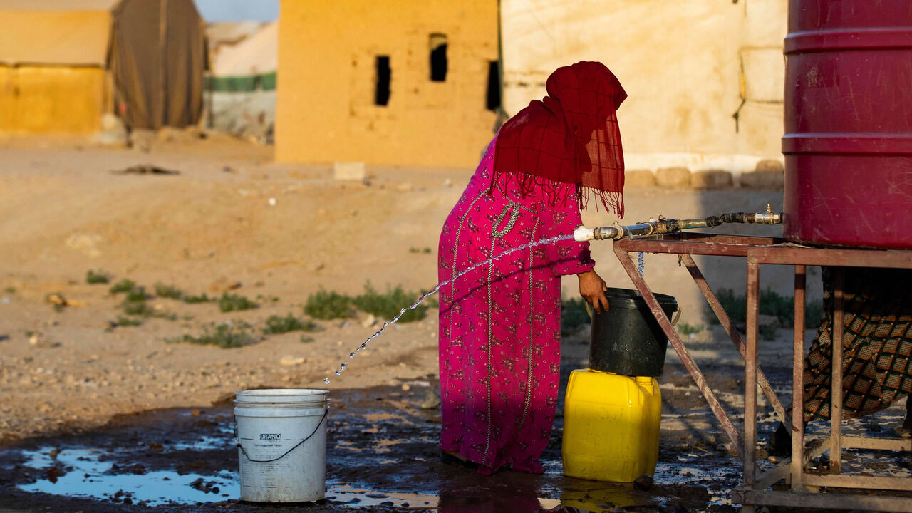 A Syrian woman fills a container with water at the Sahlah al-Banat camp in the countryside of Raqqa, northern Syria, Sept. 19, 2022.