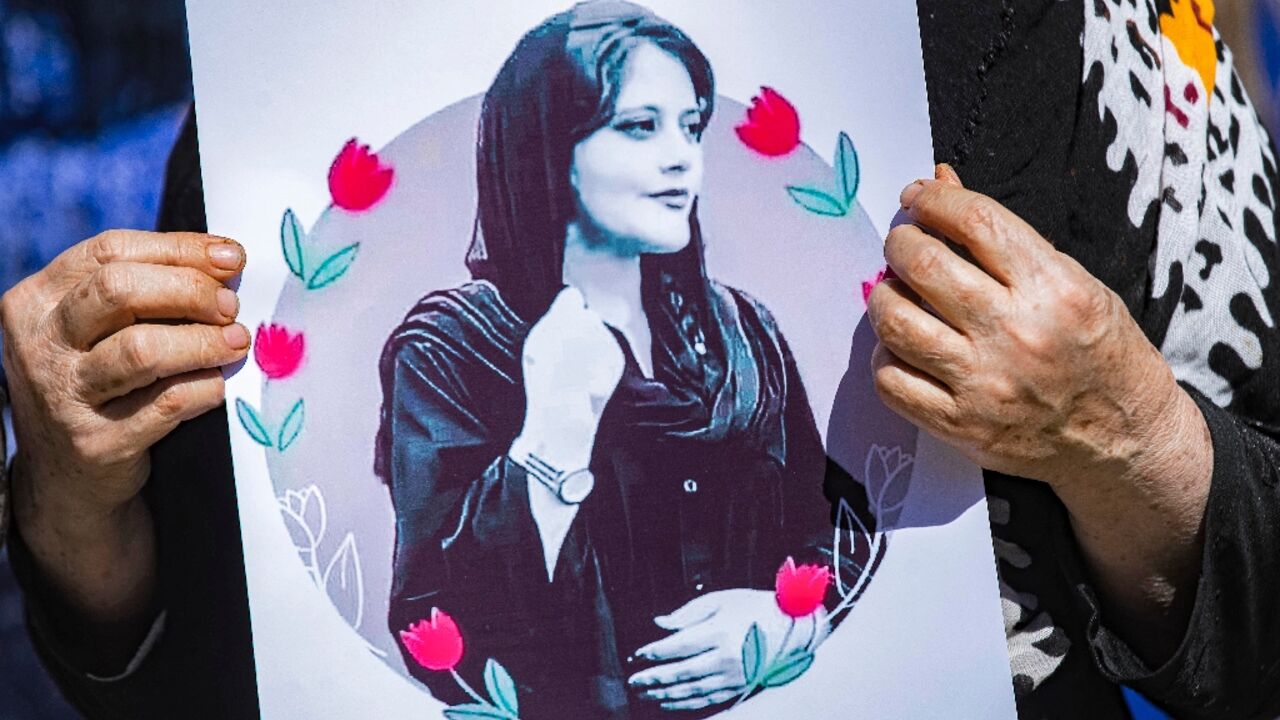 A woman holds up a picture of Mahsa Amini, the young Iranian woman who died while in Iranian police custody, at a solidarity demonstration in Syria's northeastern city of Hasakeh 