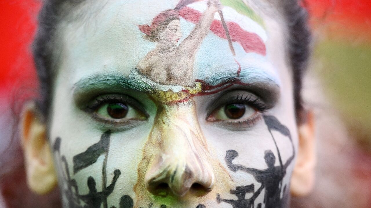 A protester wearing face-paint depicting France's iconic "Marianne" leading an uprising, attends a demonstration in support of Kurdish woman Mahsa Amini on October 2 in Paris