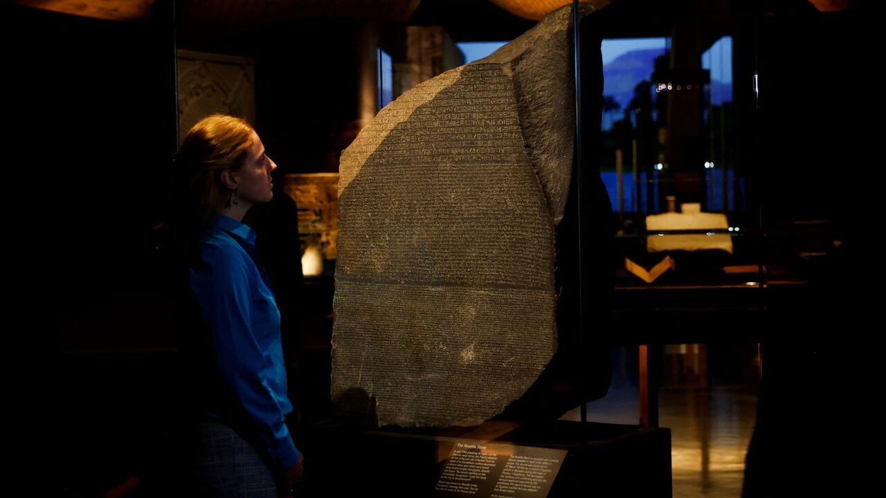 A member of staff looks at the Rosetta stone.