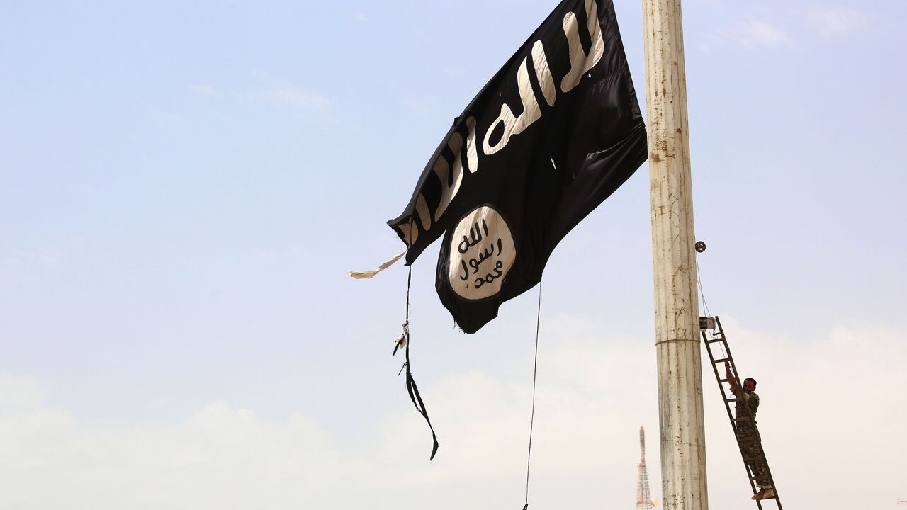 A member of the US-backed Syrian Democratic Forces (SDF), made up of an alliance of Arab and Kurdish fighters, removes an Islamic State group flag in the town of Tabqa, about 55 kilometres (35 miles) west of Raqa city, on April 30, 2017, as they advance in their battle for the group's de facto capital. 