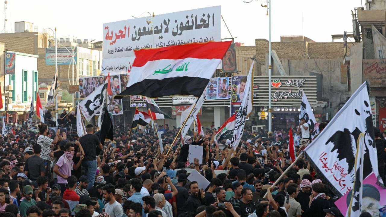 Iraqi protesters lift placards and national flags during a rally to mark three years since nationwide demonstrations erupted against endemic corruption, at al-Habboubi square in the southern city of Nasiriyah, on October 1