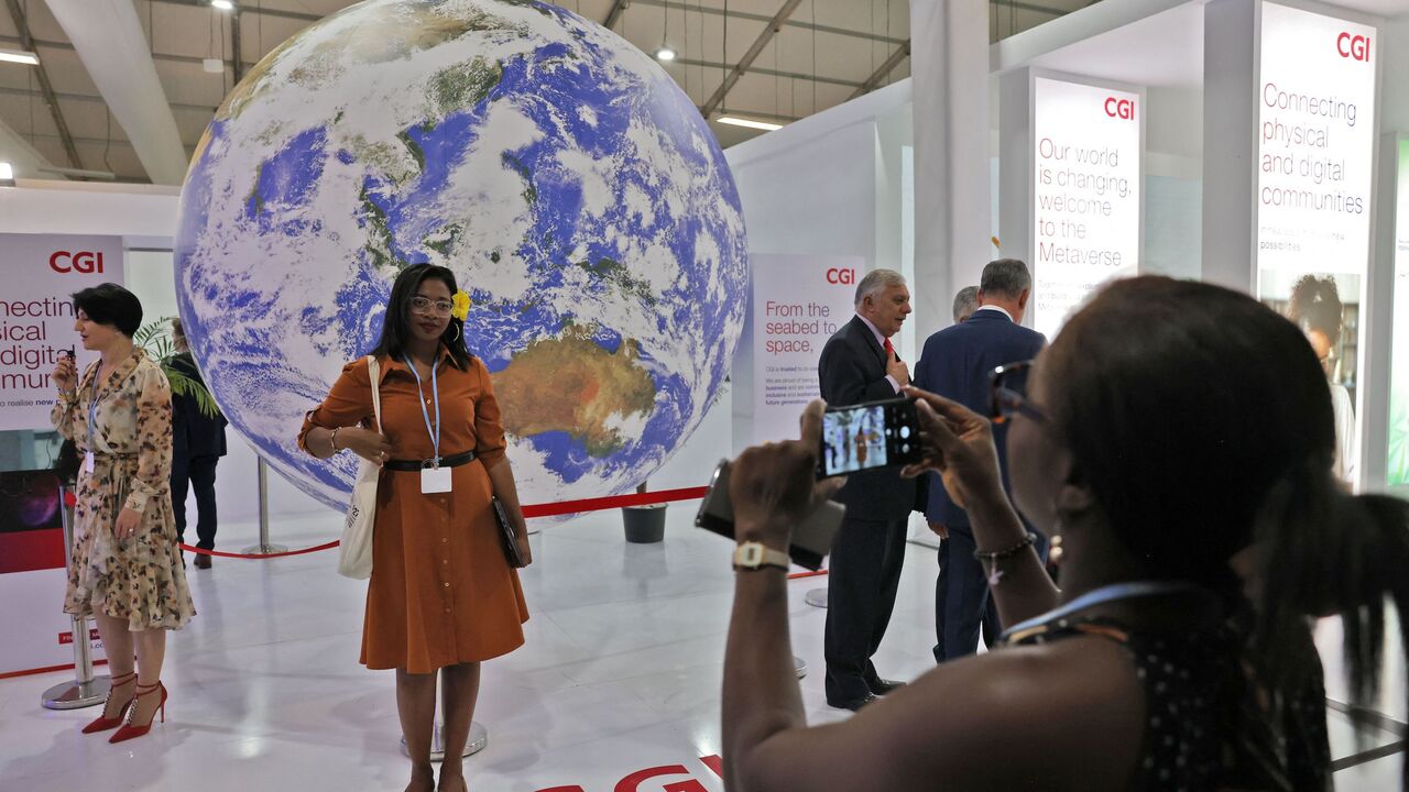 A woman poses for a picture in front of a globe on November 10, 2022, inside the venue hosting the COP27 climate conference, at the Sharm el-Sheikh International Convention Centre, in Egypt's Red Sea resort city of the same name. (Photo by AHMAD GHARABLI / AFP) (Photo by AHMAD GHARABLI/AFP via Getty Images)