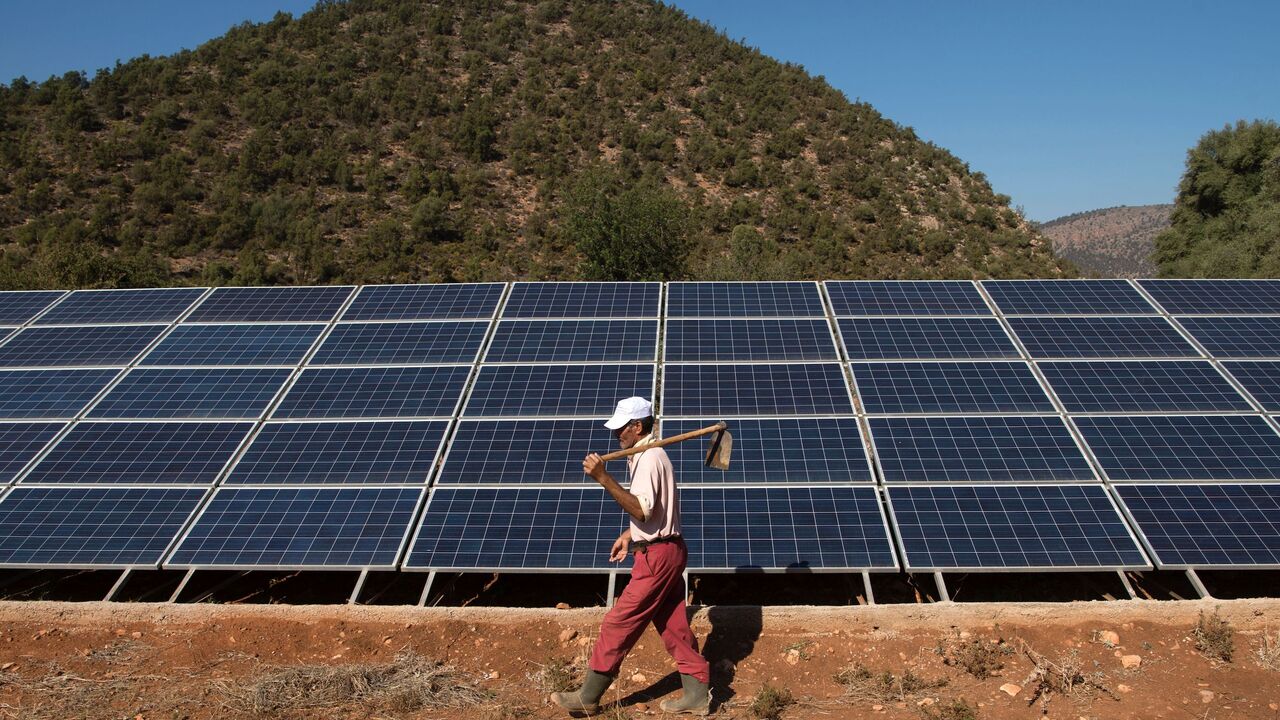 A Moroccan farmer walks past solar panels that are connected to a generator which feeds a pump extracting water from underground in Tafoughalt, a little village deep in the mountains of Morocco's eastern Berkane province, on October 31, 2016. As the Cop22 gets underway in Marrakesh, negotiators are thrashing out the details of a landmark global agreement designed to stave off disastrous climate change, but in Tafoughalt that impact is being felt already. Rising temperatures are among the factors making the