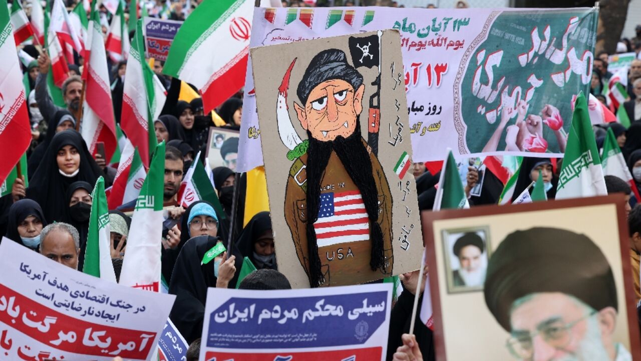 Iranians wave their country's national flag at a rally outside the former US embassy in Tehran