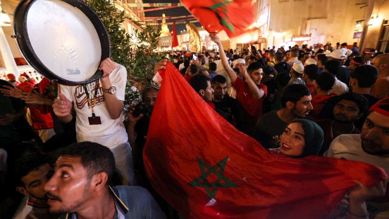 Morocco supporters in Doha's Souq Waqif celebrate their team's qualification for the last 16 of the World Cup