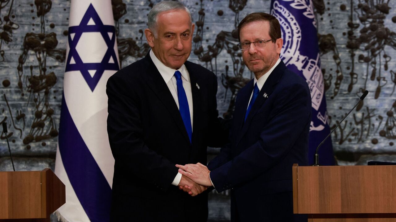 Israel's President Isaac Herzog (R) and Chairman Benjamin Netanyahu shake hands after the former tasked the latter with forming a new government, in Jerusalem, on Nov. 13, 2022.