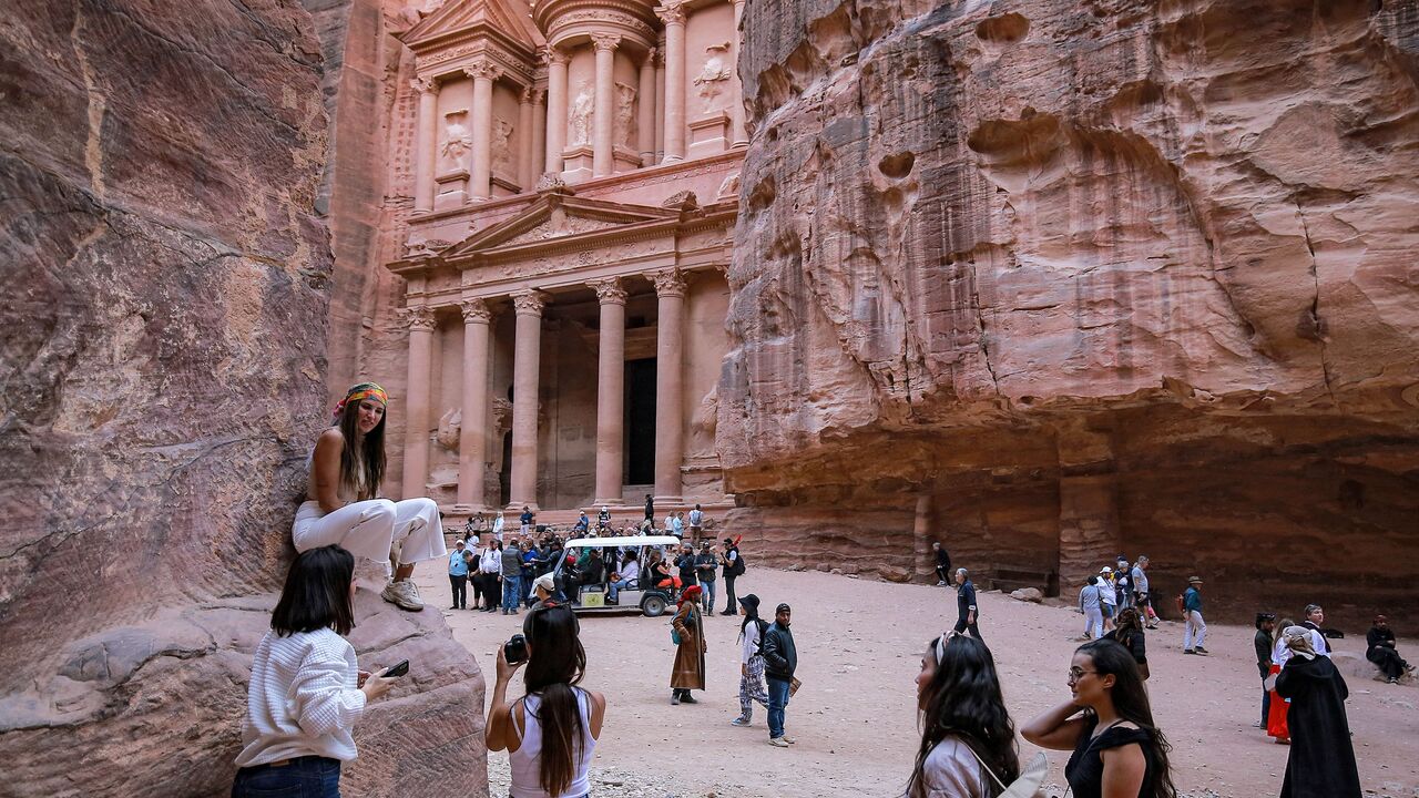 A tourist poses for a photo near the site of the Treasury at the ruins of the ancient Nabatean city of Petra in southern Jordan on on December 12, 2022. (Photo by KHALIL MAZRAAWI/AFP via Getty Images)